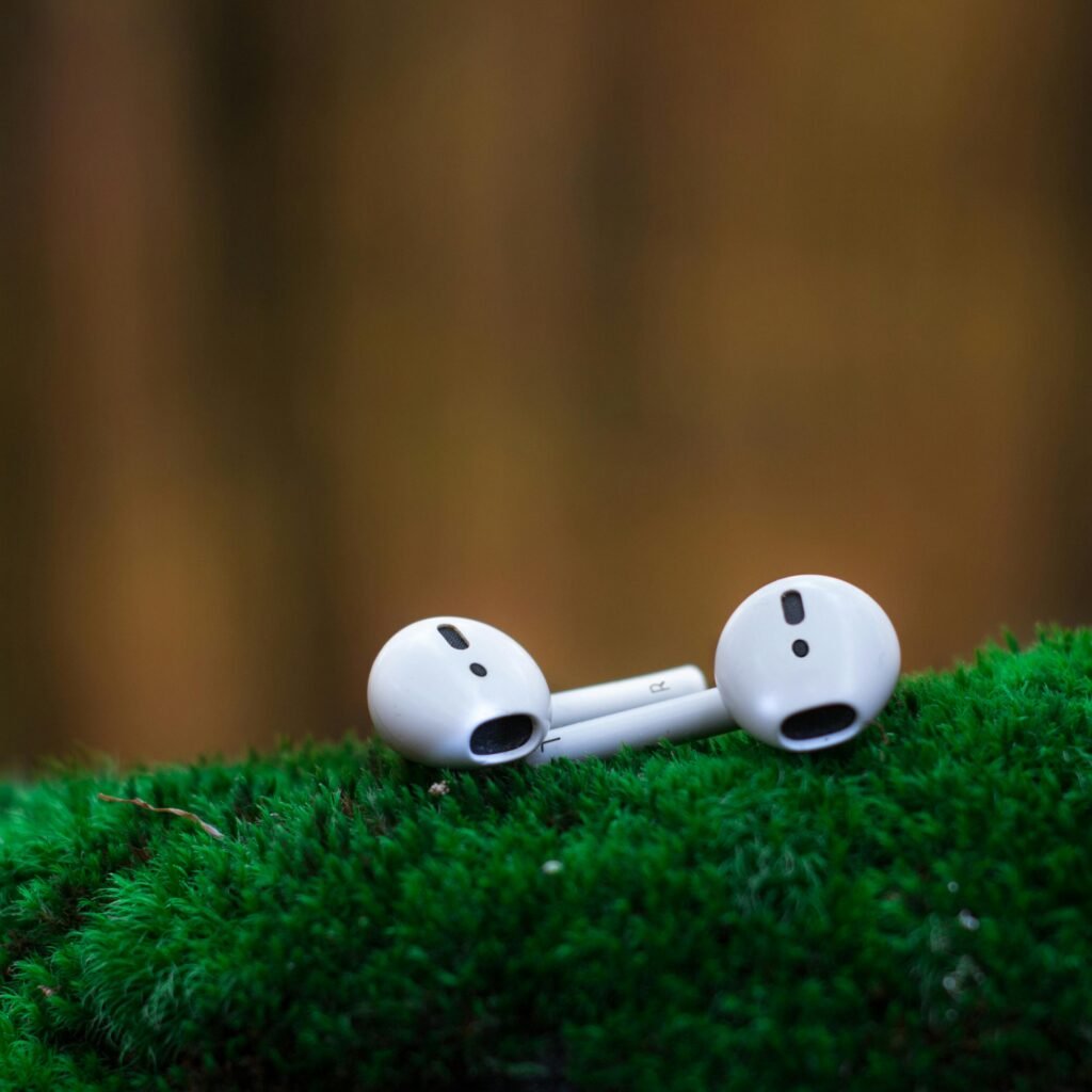 Shallow Focus Photography of White Airpods on Green Surface